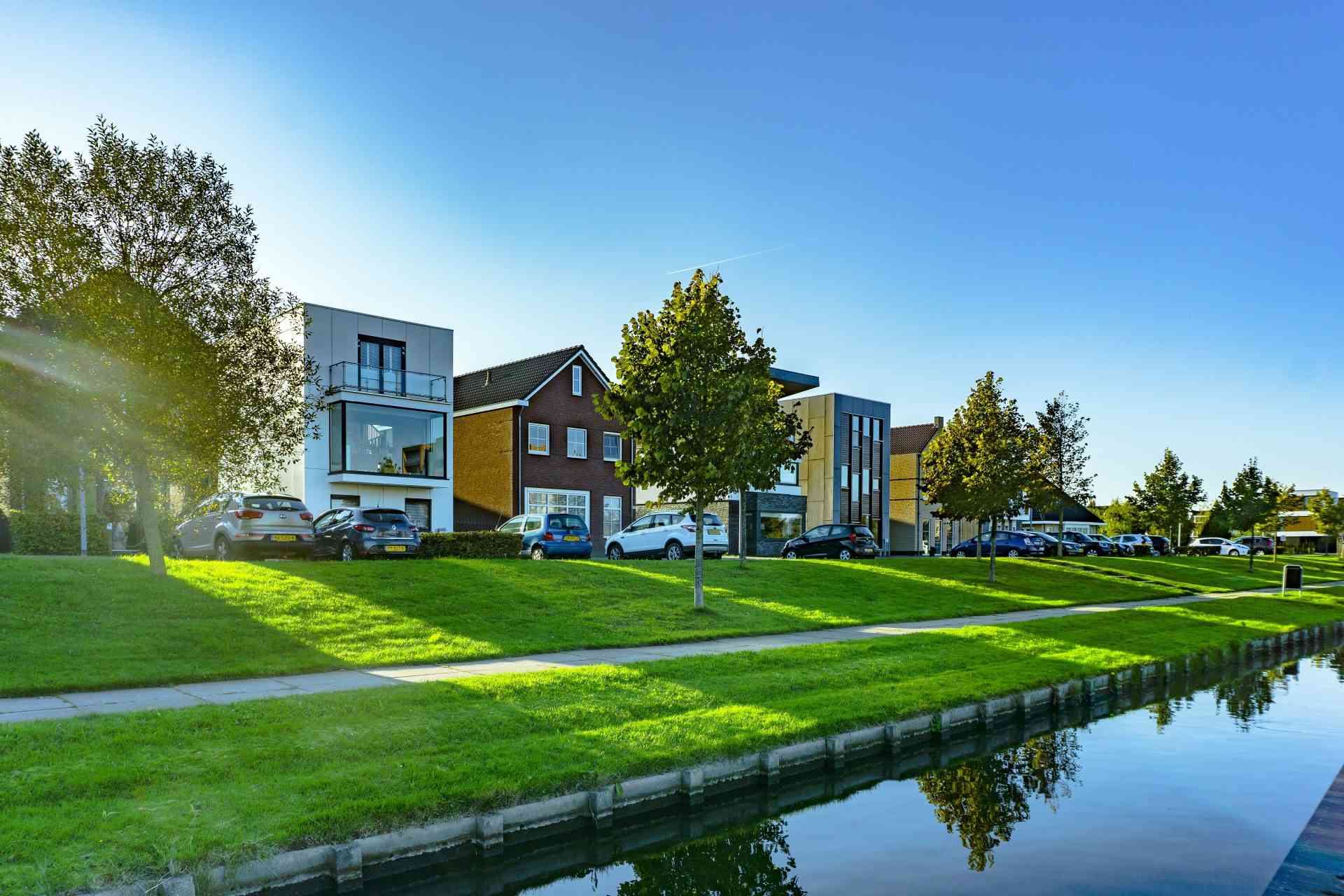 Weißes und braunes Haus in der Nähe einer grünen Wiese und eines Gewässers bei Tageslicht